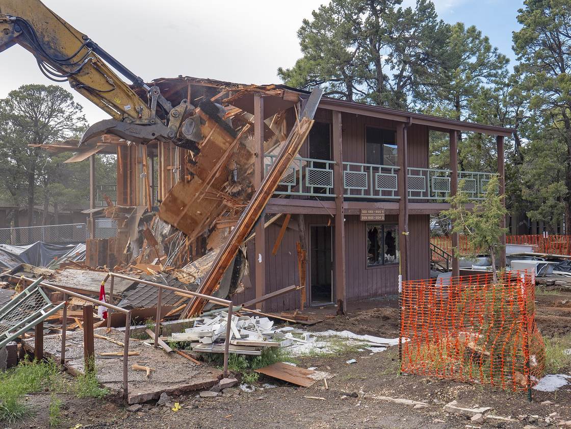 Long-reach excavator pulling down a two-story wood building